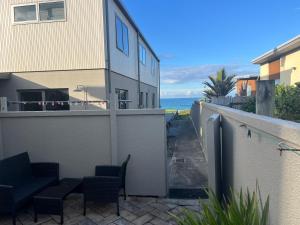 a balcony with chairs and a building and the ocean at Beachside Bliss in Tauranga