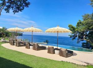una fila di sedie e ombrelloni accanto alla piscina di Bali Cliff Glamping a Karangasem