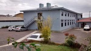 a blue building with cars parked in a parking lot at Hotel Manayara in Campo Largo