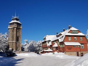 un grand bâtiment avec une tour d'horloge dans la neige dans l'établissement Apartment in Eibenstock, à Eibenstock