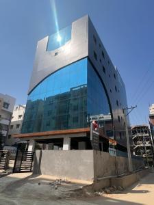 een hoog glazen gebouw met een bus ervoor bij Wild Wings Premium Hotel in Hyderabad