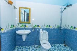 Baño de azulejos azules con aseo y lavamanos en Son River Homestay, en Phong Nha