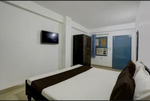 a bedroom with a bed and a tv on the wall at Roswell Nest in Gurgaon