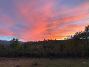 a sunset over a field with trees and bushes at Casa LUNAH Cabalgatas y Meditación in Valle de Bravo