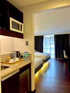 um quarto de hotel com uma cama e uma cozinha com um lavatório em The Forest Lodge at Camp John Hay with balcony and parking privately owned unit 272 em Baguio
