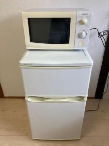 um micro-ondas sentado em cima de um frigorífico branco em TSUBAME 202 staying private home em Osaka