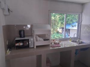 a kitchen counter with a microwave and a window at Koh Tao Townhouse in Ko Tao