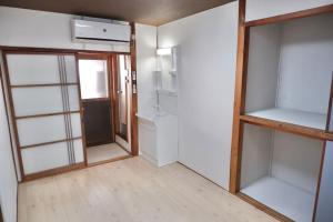 um quarto vazio com prateleiras de vidro e uma porta em TSUBAME 202 staying private home em Osaka
