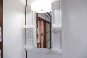 um espelho de casa de banho com uma luz na parede em TSUBAME 202 staying private home em Osaka