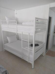 białe łóżko piętrowe z białymi półkami w pokoju w obiekcie Koh Tao Townhouse w Ko Tao