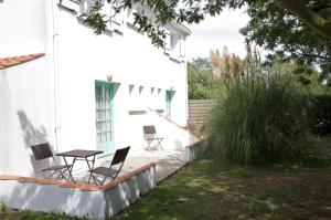 a patio with chairs and a table in a yard at Hotel Autre Mer in Noirmoutier-en-l'lle