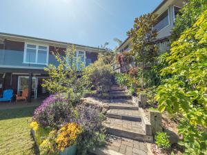 a garden in front of a house with flowers at Brophys Beach Studio in Whitianga