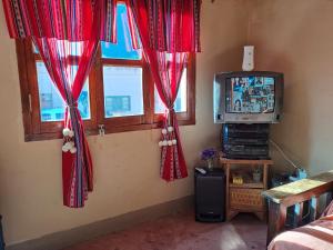 sala de estar con cortinas rojas y TV en ILLARI en Maimará