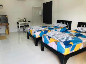 two beds in a room with a table and a desk at แหลมงอบเฮาส์ laemngob House in Laem Ngop