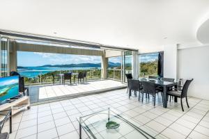 Ocean Sunsets - Skiathos في جزيرة هاميلتون: غرفة معيشة مع طاولة وكراسي وتلفزيون
