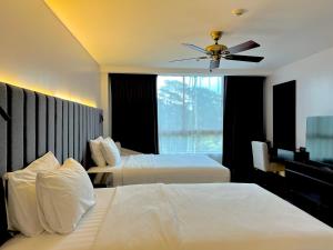a hotel room with two beds and a ceiling fan at Forest Lodge at Camp John Hay privately owned - Deluxe Queen Suite with balcony and Parking 269 in Baguio