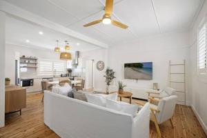a living room with white furniture and a ceiling fan at Coastal Dreams with Playground & Pets Welcome in Ettalong Beach