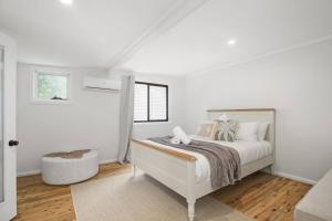 a white bedroom with a bed and a window at Coastal Dreams with Playground & Pets Welcome in Ettalong Beach