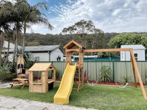 a wooden playground with a slide and a play structure at Coastal Dreams with Playground & Pets Welcome in Ettalong Beach