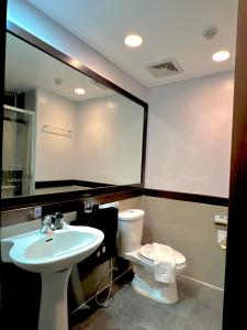 een badkamer met een wastafel, een toilet en een spiegel bij The Forest Lodge at Camp John Hay privately owned unit with parking 371 in Baguio