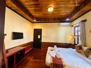 a bedroom with a bed and a flat screen tv at Ammata Boutique Villa in Luang Prabang