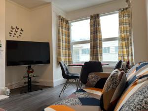a living room with a tv and two windows at **Dream Home** Near Seaside (Southend on Sea) in Southend-on-Sea
