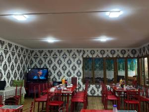 a dining room with tables and red chairs and a tv at Central Park Hostel in Khiva