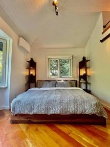a bedroom with a large bed and two windows at Sauna + Spa @ Boho House on Bowen Island in Bowen Island