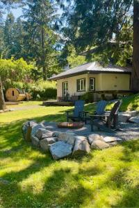 a backyard with a fire pit and two chairs and a house at Sauna + Spa @ Boho House on Bowen Island in Bowen Island