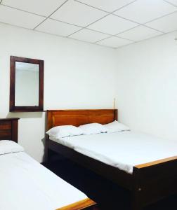2 camas en una habitación con espejo en la pared en Thissawewa Guest en Anuradhapura