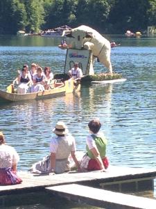 a group of people sitting on a dock in boats in the water at Appartements direkt am See in Grundlsee