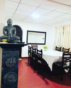 ein Esszimmer mit einem Tisch und einer Statue in einem Raum in der Unterkunft Thissawewa Guest in Anuradhapura