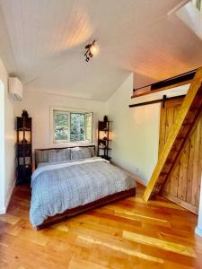 a bedroom with a bed and a wooden floor at Sauna + Spa @ Boho House on Bowen Island in Bowen Island