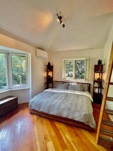 a bedroom with a bed and two windows at Sauna + Spa @ Boho House on Bowen Island in Bowen Island