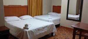 a hotel room with two beds and a mirror at HOSPEDAJE BUENA VISTA in Ayacucho