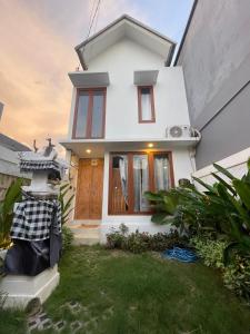 une maison blanche avec une pelouse devant elle dans l'établissement LaKalena Private Villa Bali, à Ketewel