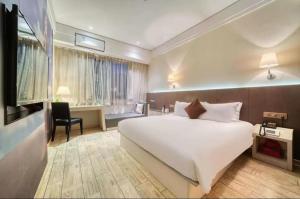 um quarto com uma grande cama branca e uma secretária em Hansen Hotel em Hangzhou
