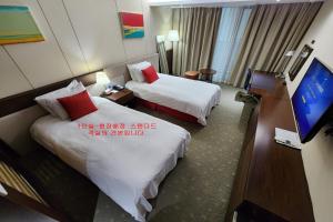 um quarto de hotel com duas camas e uma televisão de ecrã plano em Ramada by Wyndham Jeju Hamdeok em Jeju