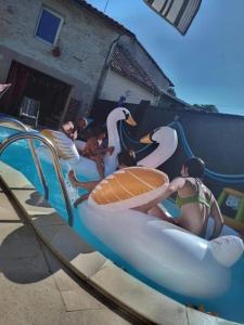 un grupo de personas en botes hinchables de cisne en una piscina en Chambre pour 2 personnes avec un lit, en Chef-Boutonne