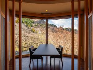 a table and chairs in a room with a large window at Nagominoyado Hanagokoro - Reopening in Mar 2024 in Hakone