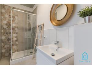 uma casa de banho com um lavatório e um chuveiro com um espelho. em Glamour Apartment em Gdansk