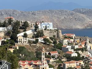 una ciudad en una colina con casas y un cuerpo de agua en Aleminas Rooms, en Symi