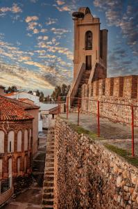 a building with a clock tower behind a stone wall at La Casina de Palacio in Galisteo
