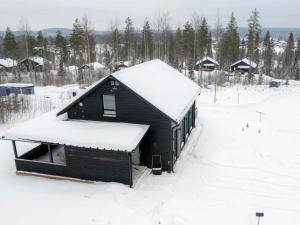 a black cabin with snow on the roof at Tähtitaivas in Jämsä