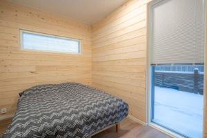 een slaapkamer met een bed in een houten kamer met een raam bij Tähtitaivas in Jämsä
