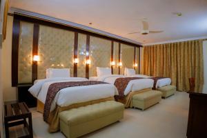 a hotel room with three beds and two chairs at Indus Hotel in Hyderabad