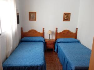 2 camas en una habitación pequeña con sábanas azules en Adosado con garaje privado - Junto al mar, en Los Nietos