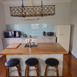 a kitchen with a wooden counter top and three stools at Che Bella in Martinborough