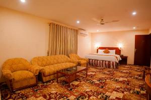 a hotel room with a bed and a couch and a table at Indus Hotel in Hyderabad