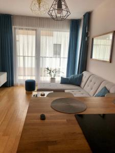 ein Wohnzimmer mit einem Sofa und einigen Fenstern in der Unterkunft Cosy apartment green&quiet Ursynów in Warschau